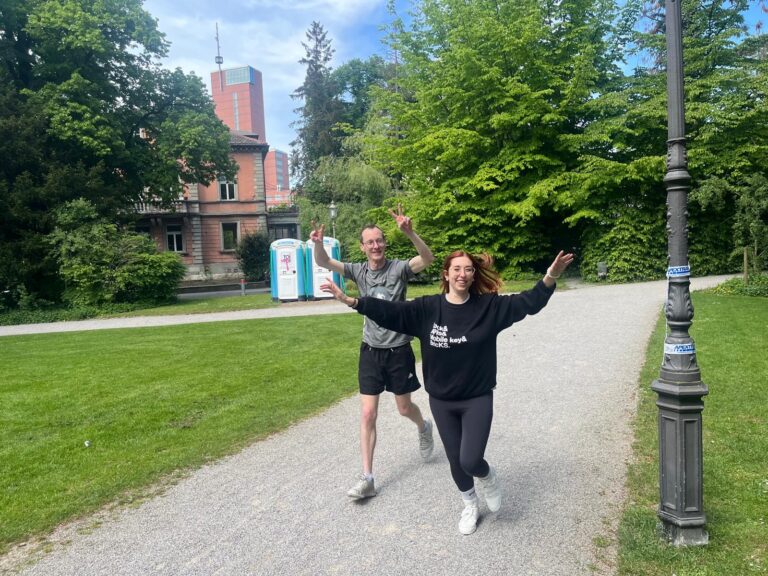 Ein Mann und eine Frau laufen fröhlich auf einem Kiesweg in einem Park.