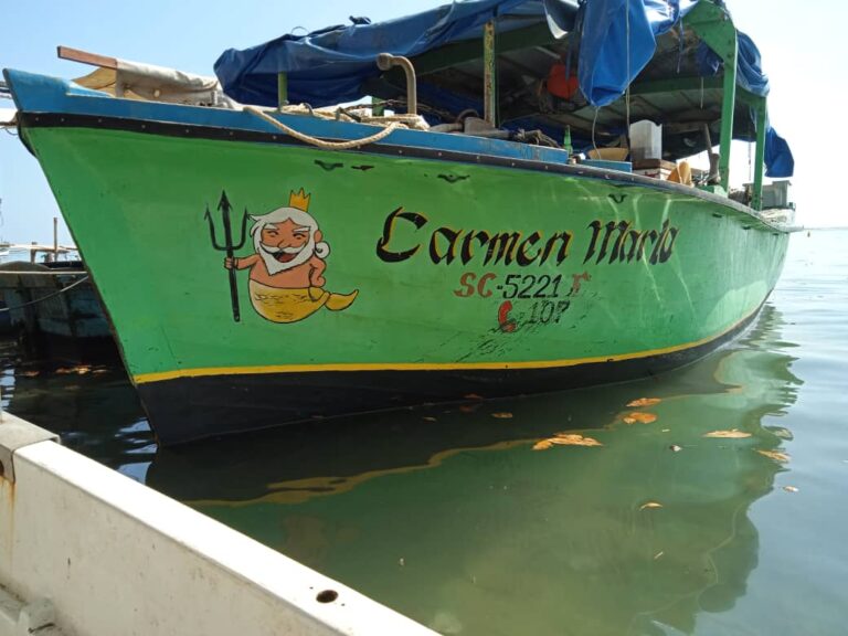 Ein Fischerboot mit dem Namen "Carmen Maria" liegt in einem Hafen.